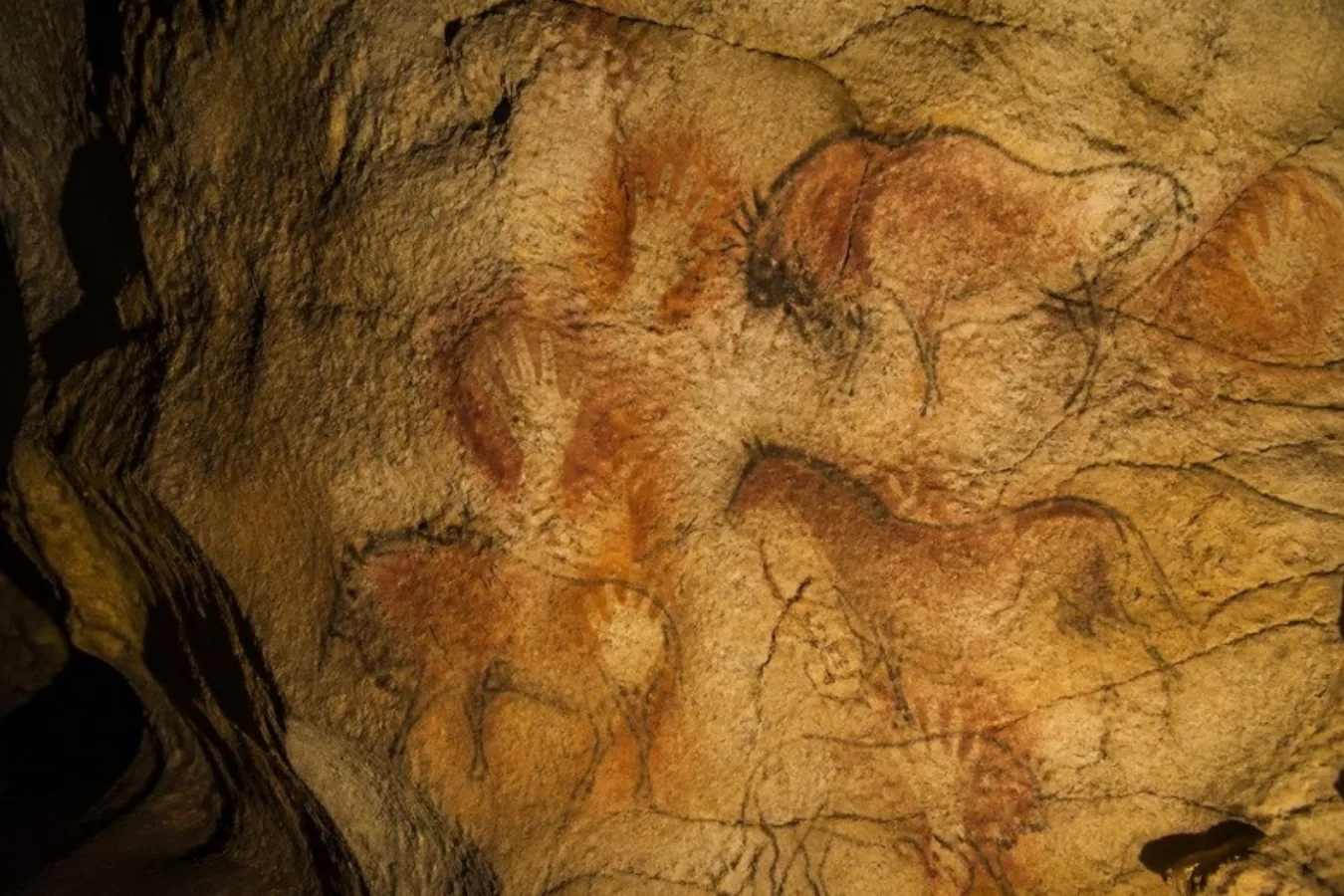 An illustration in the style of prehistoric cave art, with hand stencils and animals in red ochre