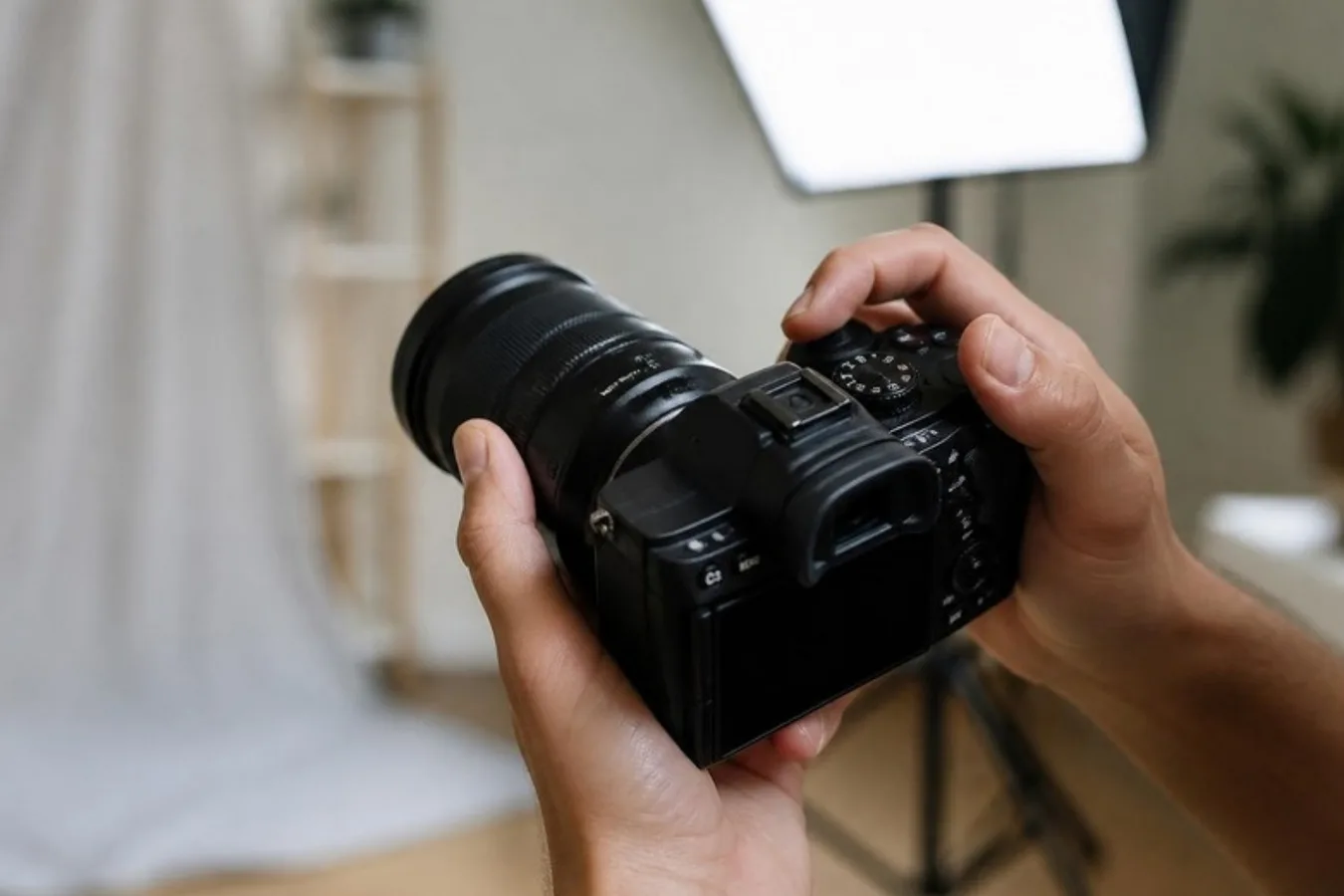 Hands holding a camera with a portrait lens in a home studio
